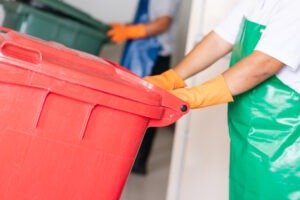 A woman worker holding red bin.