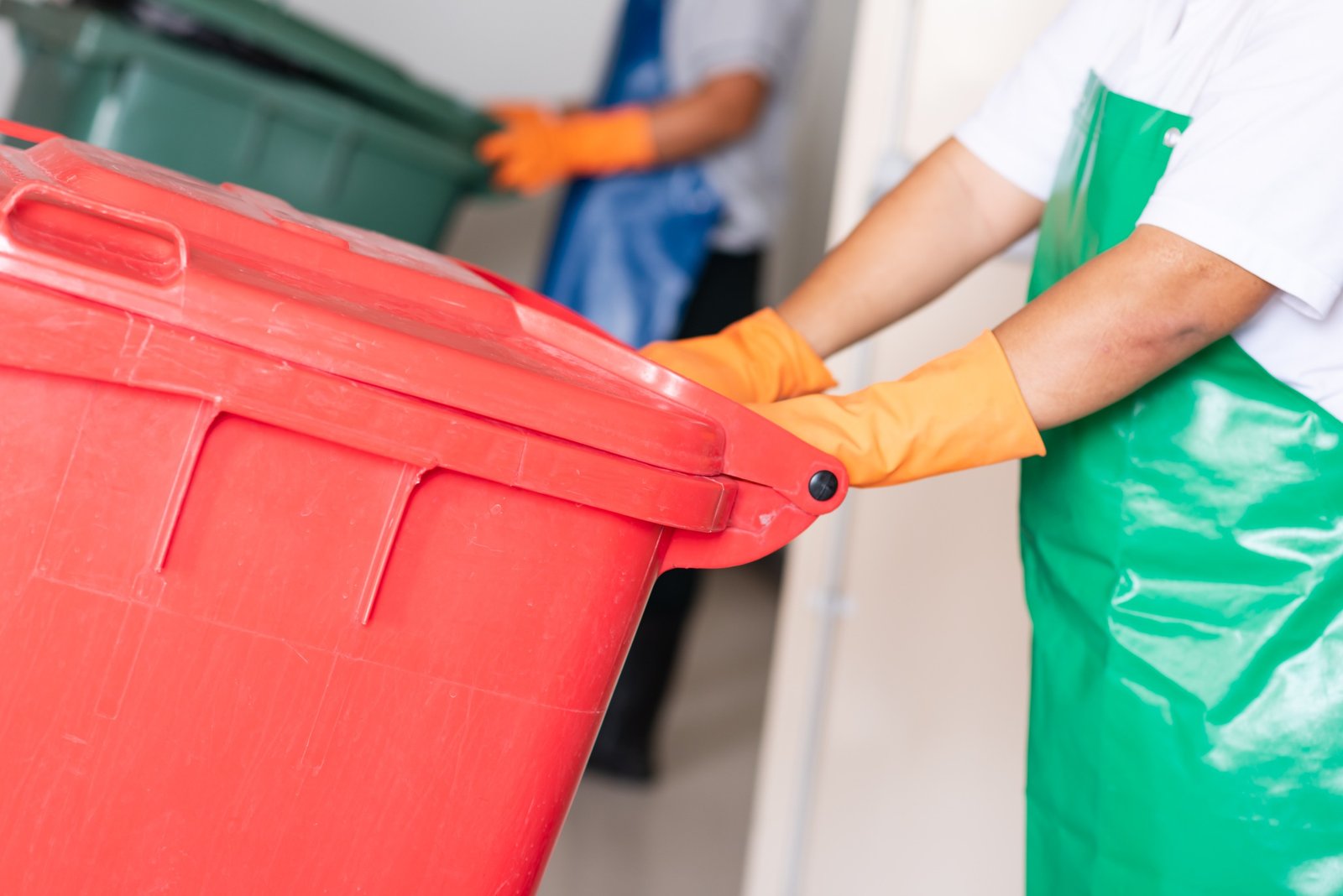 A woman worker holding red bin.